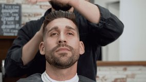 Barber shop. Man in barber's chair, hairdresser styling his hair. High quality 4k footage