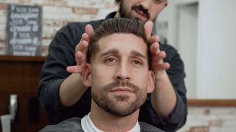 Barber shop. Man in barber's chair, hairdresser styling his hair. High quality 4k footage