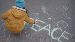 Top view of little girl writing peace with chalk. Protest against Russian invasion of Ukraine. - Powered by Shutterstock - Get 15% off with code: PIKWIZARD15