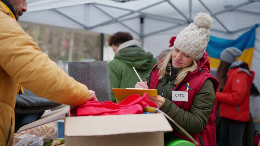 Volunteers distributing blankets and other donations to refugees on the Ukrainian border. | Shutterstock HD Video #1088519975