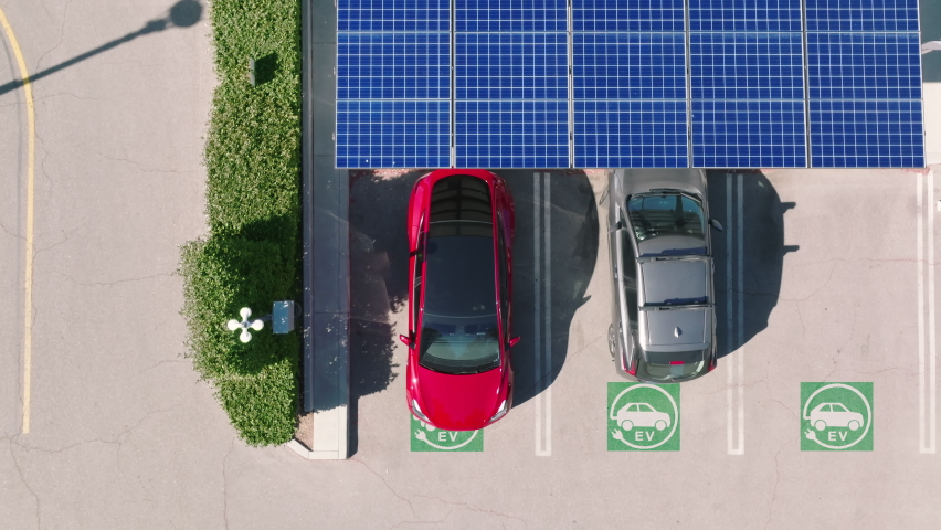 Aerial view of a car parking under solar panels. 4K electric, zero pollution cars on green energy concept on modern city parking lot. Alternative energy for ecological cars under blue solar batteries Royalty-Free Stock Footage #1088521503