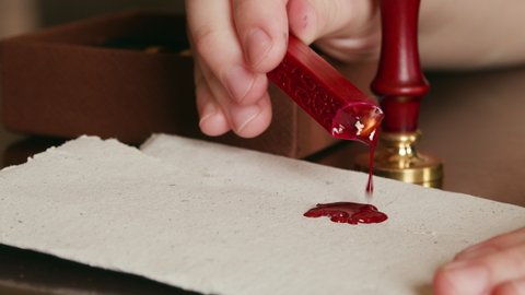 Dripping hot wax onto a piece of parchment in preparation for a wax seal.