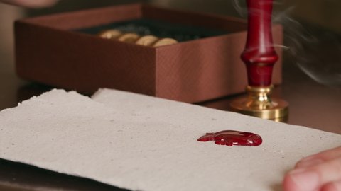 Pressing a wax seal into hot wax on a piece of parchment, sealing the letter.