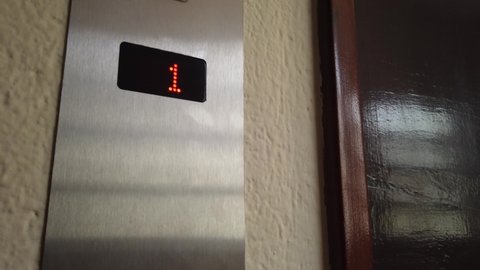 Rio de Janeiro, RJ, Brazil - March 21st 2022 - Elevator panel led showing an arrow up, and floors 1 and 2. Elevator Lift going up.  Elevator wooden door and silver steel panel. Elevator button