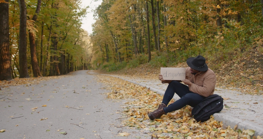 Young hitchhiker with a sign on the roadside