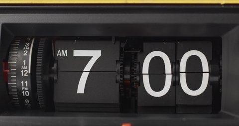 Retro Flip Clock Showing at 7:00 a.m.Spinning timelapse, on black background.