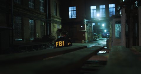 An FBI agent investigates the crime scene at night. Illuminating dark corners with a flashlight, the agent searches for clues.