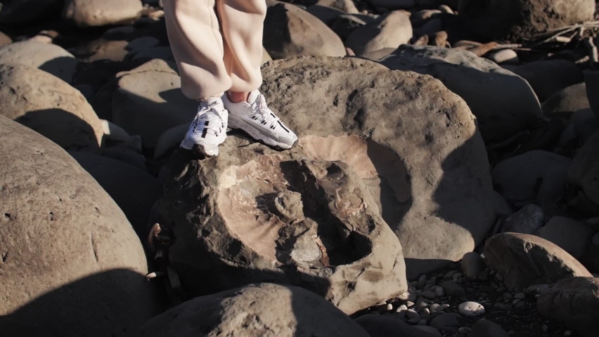 footage of ancient fossils, ammonites, large stones, the girl walks on the stones
