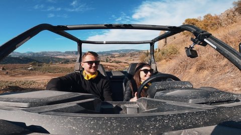 Young couple driving a buggy UTV ATV Can-am polaris on desert off-road in Ronda, Spain, on a sunny day . Couple having fun riding a ATV off-road.