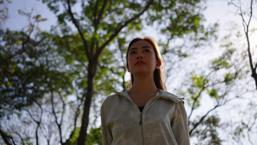 Asian woman in sportswear and smartwatch stretching body while jogging exercise at public park in the city in the morning. Healthy female athlete enjoy outdoor lifestyle sport training running workout