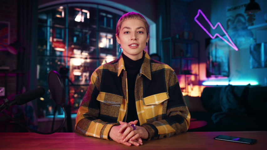 Ecstatic Young Female with Short Hair Talking Into Microphone While Recording Podcast from Loft Apartment. Happy Surprised Woman Talking on Camera and Recording Radio Show Live on Social Media.