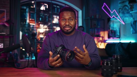 Young African American Man Talking, Reviewing Tech Stuff While Recording a Podcast About New Photography Camera and Video Equipment. Confident Black Male Explaining New Features Live on Social Media.