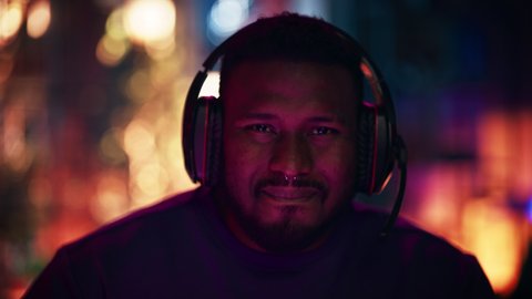 Close Up Portrait of a Black Stylish Young Man with Nose Ring Playing Online Computer Video Game in the Evening at Home. Gamer Discussing Tactics with Teammates while Talking into Headset.