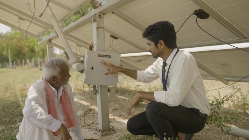 Engineer explaining to Indian farmer about sloar power generation operating below the panel module at agricultural farm land - concept of modren agriculture and sustainable future Royalty-Free Stock Footage #1088540555