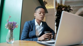 African American female holds an online meeting uses a laptop for a video call, works in a cafe, during a tourist business trip, black woman, businesswoman works remotely. Conference communication