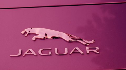 LONDON, UNITED KINGDOM - NOVEMBER 8, 2014: Jaguar Motors pink car - panning to logotype on the street. Panning left to right. Jaguar Cars is a brand of Jaguar Land Rover