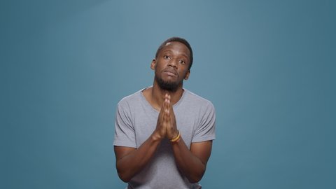 Hopeful man doign prayer gesture with hands in front of camera, begging and imploring for trust and fortune. Wishful person praying and asking for forgiveness, please and apologize pose.