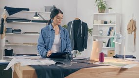 A Professional Fashion Designer Creates a New Collection, Draws, Works with Sketches Using a Laptop in a Fashion Business Startup Studio. Concept of Handmade, Manual Labor, Fashion and Couturier.