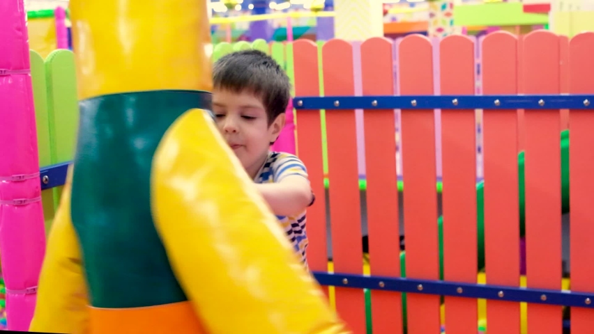 A preschool boy of 4 years old plays with a punching bag for boxing in the playroom, a children