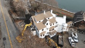 House being ripped apart by heavy machinery, aerial static drone footage.