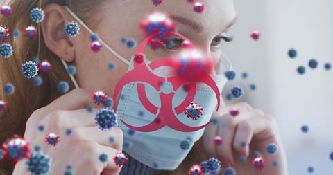 Animation of virus cells and biohazard symbol over caucasian woman with face mask. lifestyle during covid 19 pandemic concept digitally generated video.
