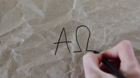 Human handwriting Greek letters alpha and omega on a crumpled paper with marker.