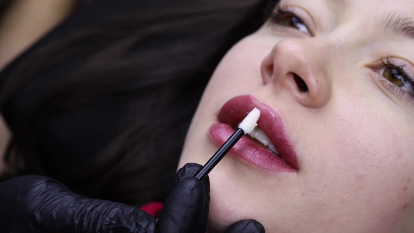 close-up of the procedure for permanent makeup of the lips, the master erases the remnants of the pigment from the lips Royalty-Free Stock Footage #1088554147