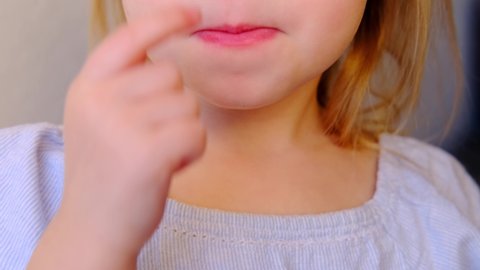 close-up of part of small child, blonde girl 3 years old picks his nose with his finger, rubs the skin, happy childhood, concept of runny nose, allergies, virus, bad habits, unhealthy food