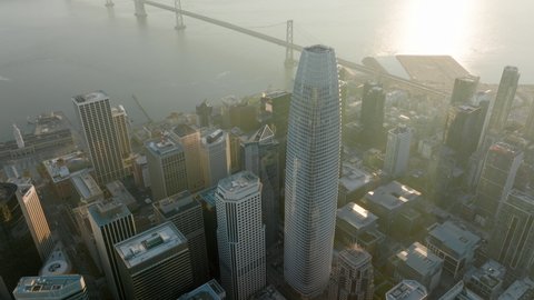 Cinematic view on golden sunrise light reflecting from water in San Francisco bay area at business offices district. 4K aerial glass buildings architecture with American cityscape on motion background