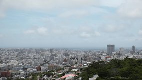 NAHA, OKINAWA, JAPAN - AUG 2021 : Aerial high angle wide view of Naha city. Cityscape of downtown area and sunny blue sky. Time lapse shot in daytime. Summer holiday, vacation and travel concept video