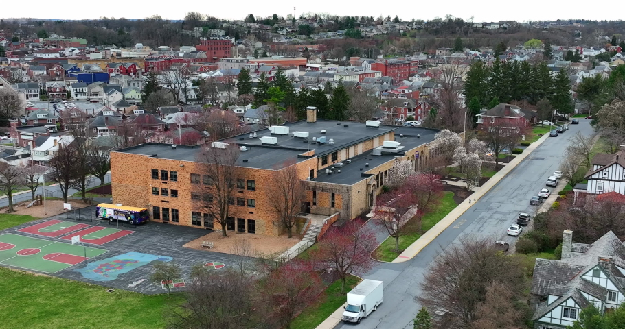 Urban city school in USA. Aerial parallax shot of building in town in United States. American education system theme. Neighborhood homes. Royalty-Free Stock Footage #1088561177