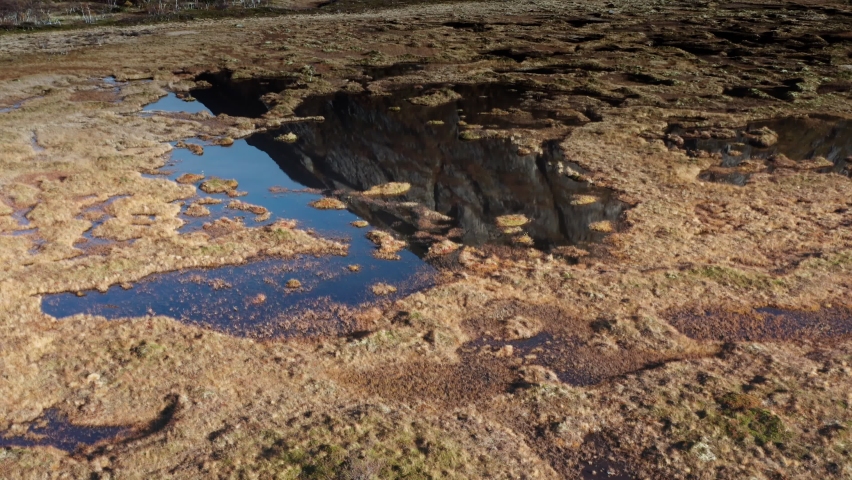 Aerial view of the swampy wetlands in northern Norway. Blue sky reflected in the mirrorlike waters. Slow-motion.