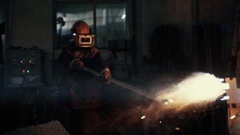 Laborer is working near the hot and dangerous furnace at the Production Factory. A worker is throwing coal into the hot dangerous furnace. Industrial Dangerous furnace creates hot sparks. Slow motion