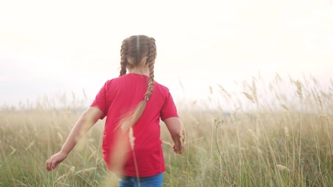 little girl running across the field in nature in the park. happy family kid dream concept. little girl running in dry grass in wild park. free girl happy fun childhood and family concept