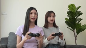 Two Asian women are enjoy playing game in the bed with joystick on their holiday.  