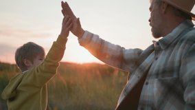 Family in village. Affectionate father walking with his son on field, doing high-five and enjoying summer evening adventure in open nature. Team. Relationship. - Powered by Shutterstock - Get 15% off with code: PIKWIZARD15