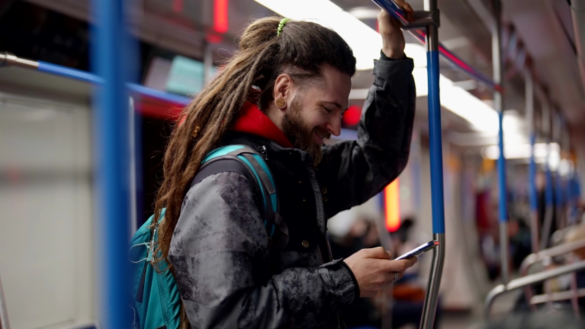 young man is reading news in internet and social media by smartphone in metro train