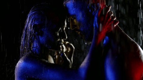 close-up of a couple with golden metallic skin. they closed eyes and touched each other at night in the rain. red, blue and white light. the dark key. profile view