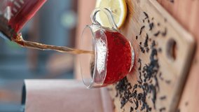 VERTICAL VIDEO POV pouring fresh fragrance black hot tea from teapot to transparent glass cup at kitchen slowmo. Serving cuisine wooden table for morning breakfast appetizing break relaxation  - Powered by Shutterstock - Get 15% off with code: PIKWIZARD15