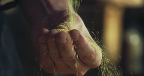 Cinematic macro of professional artisan baker chef sprinkles corn flour dust powder on table while kneading dough for preparation of breads, gluten-free baking and fried foods in rustic bakery kitchen