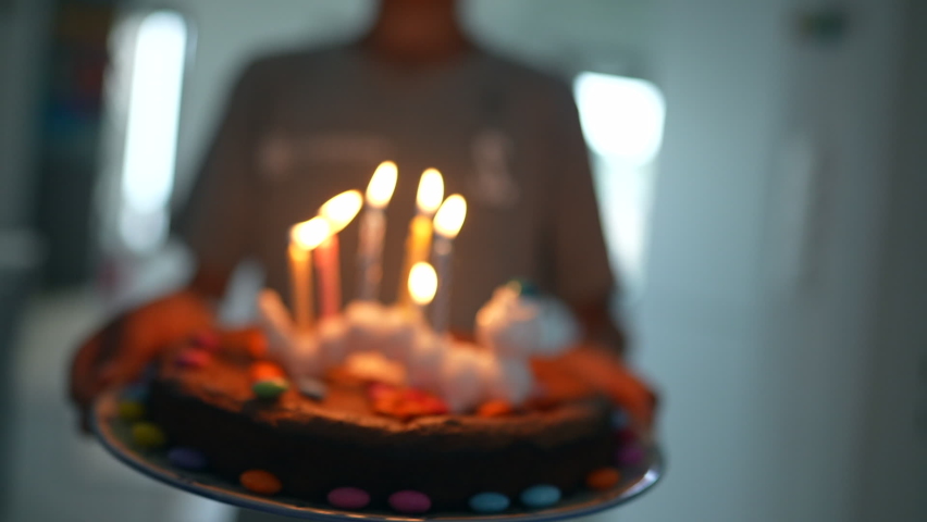 Person holding birthday cake with five candles