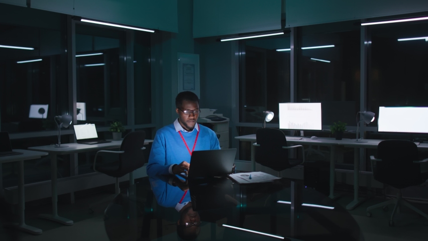 African-American manager shake head looking at laptop screen working late in dark office. Businessman work on computer in empty office at night Royalty-Free Stock Footage #1088572883
