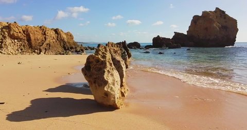 Slowed down view of a wave crashin breaking on a rock cliff. Calming water texture breaking on beach. Sea wave crash, rocky coastline. Beautiful blue ocean. Portugal, Algarve region. No people. 