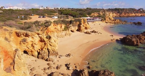 Aerial view over beautiful tropical beach with golden sand, empty and clean beach, no people. Turquoise blue ocean with cliffy shoreline. Famous Algarve tourist destination, Portugal. Lonely sand 