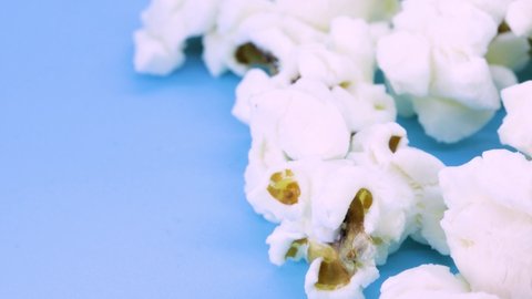 Extreme close up view of popcorn rotating on blue surface, close up view in 4k.