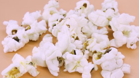 Close up view of popcorn rotating on orange surface, 4k macro shot.