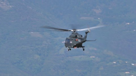 Thiene Italy OCTOBER, 16, 2021 Helicopter low flying in blue sky with green forest on mountains in background. AgustaWestland AW139 Leonardo of Italian Air Force