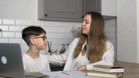 The boy does his homework and shows the results to his older sister. The girl praises her younger brother for good studies. Study