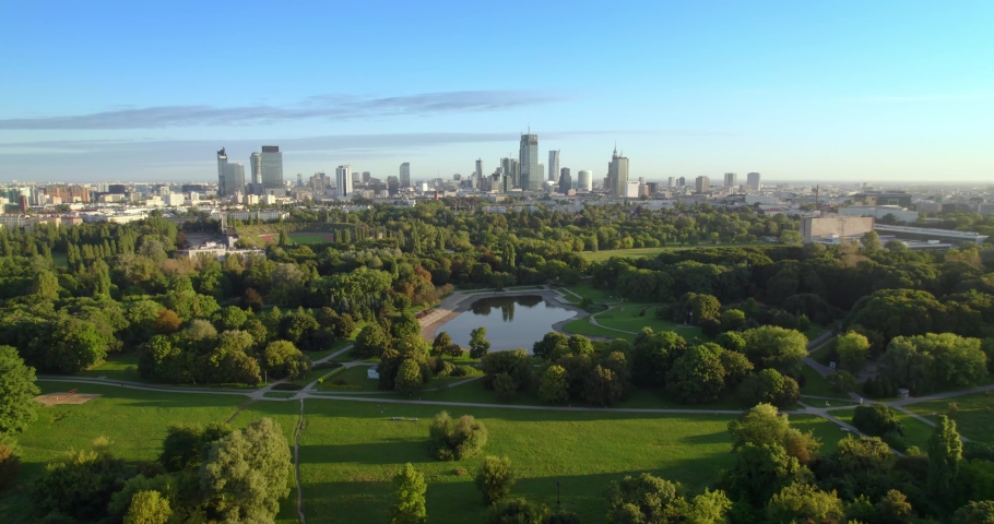 City park with the city center in the background. Aerial view of offices in skyscrapers over the panorama of Warsaw in a urban park. Lake in the park with green trees during summer. Royalty-Free Stock Footage #1088578181
