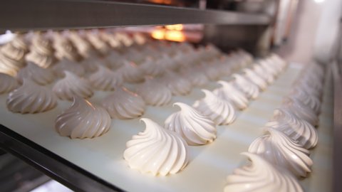 Slowly moving conveyor belt with fresh creamy marshmallows. Close up. Sweet vanilla desserts come from a dryer.